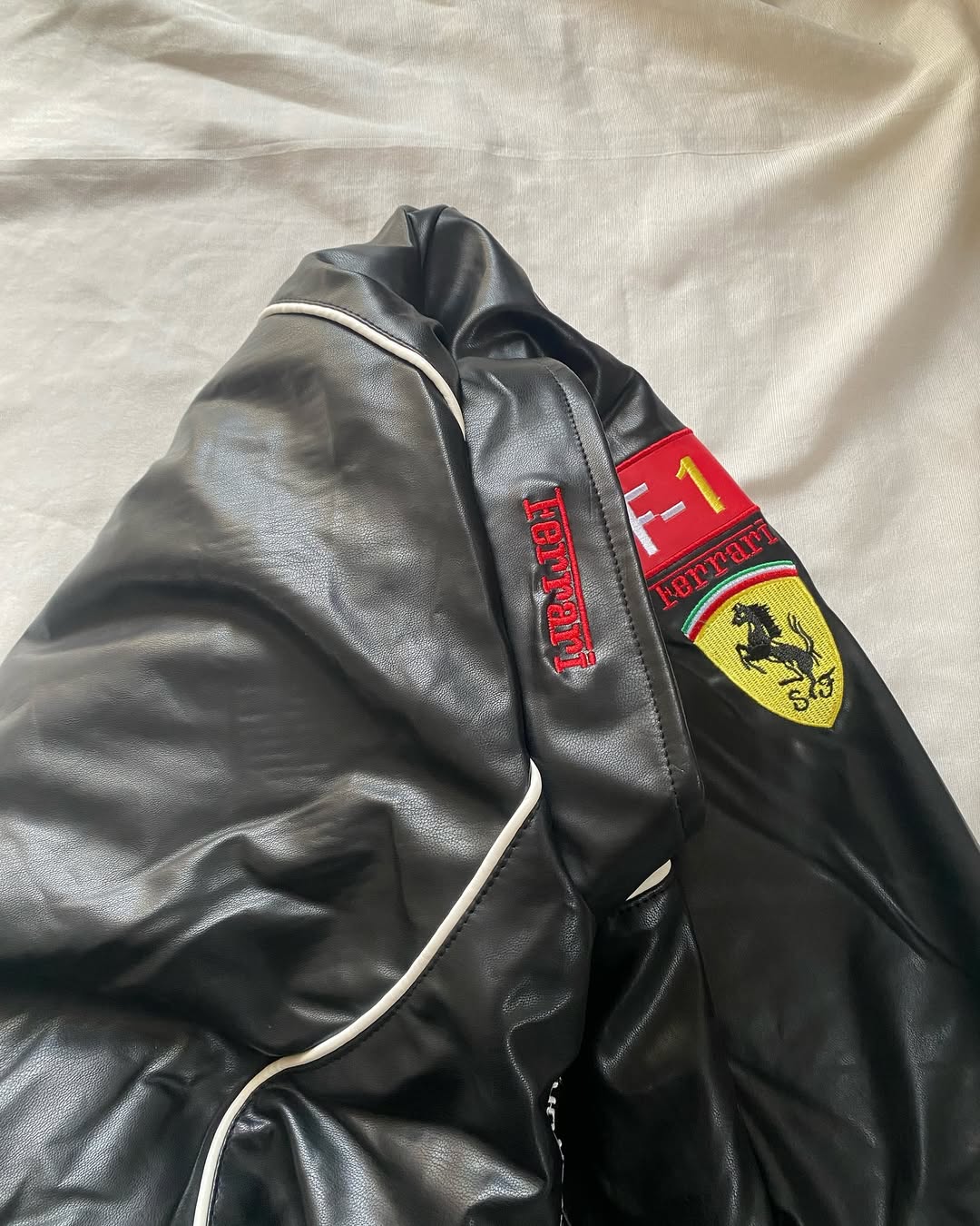 Black leather racing jacket sleeve with red trim and Ferrari-style shield patch
