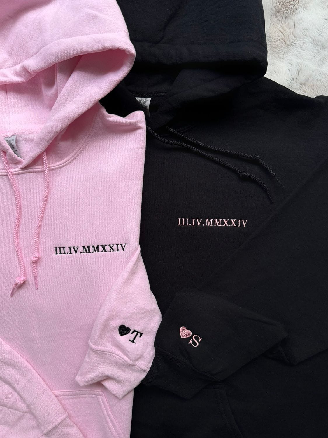 Pink and black couple hoodies, front logos and heart icons on the chest and pocket.