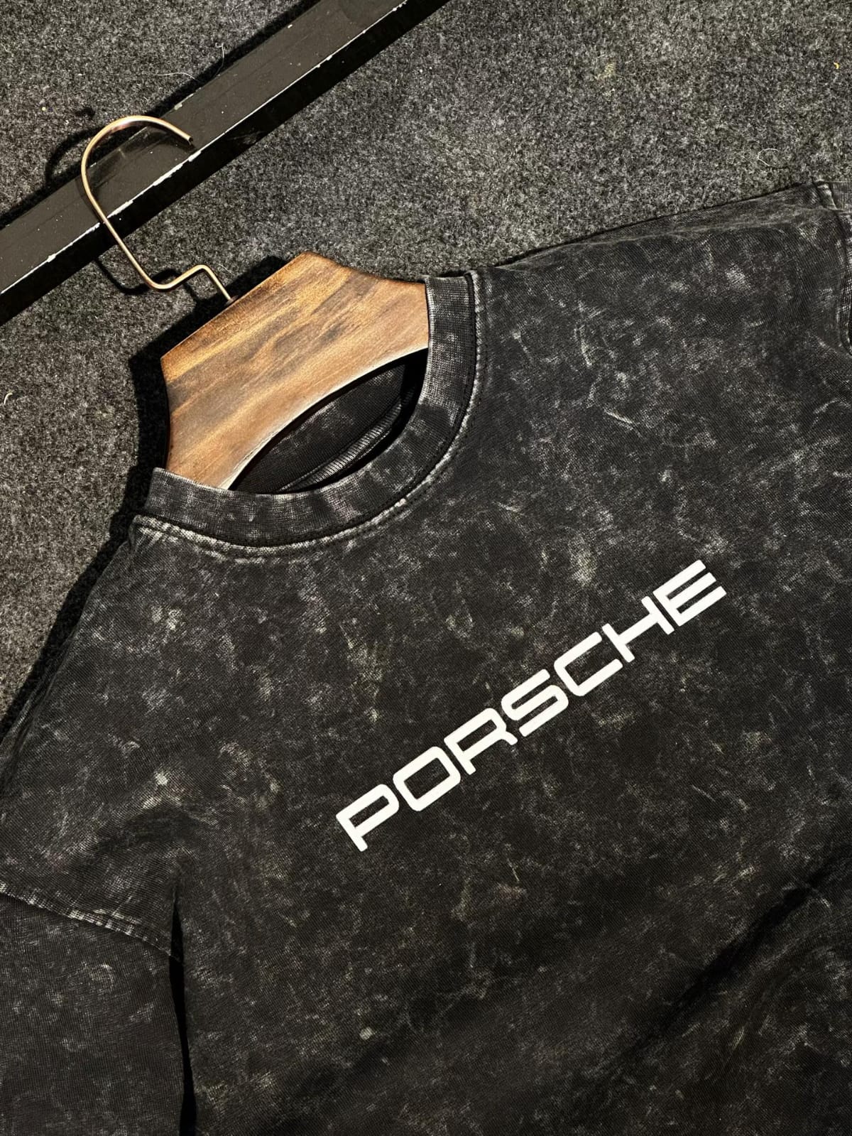 Dark acid-wash T-shirt close-up with PORSCHE lettering across the chest
