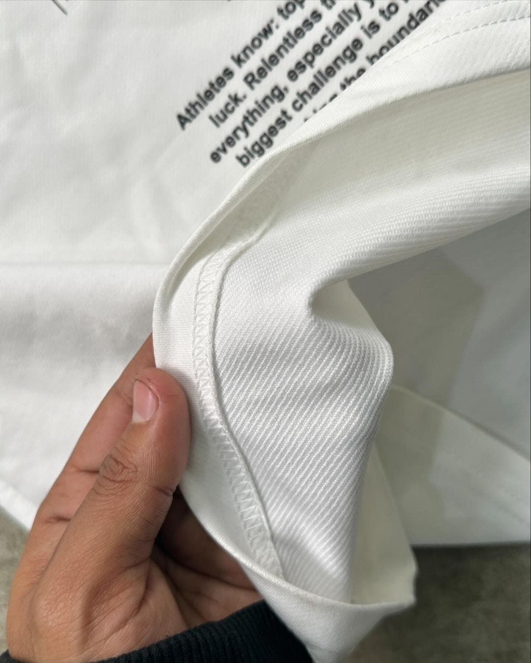 White T-shirt fabric closeup with sleeve seam and curved hem