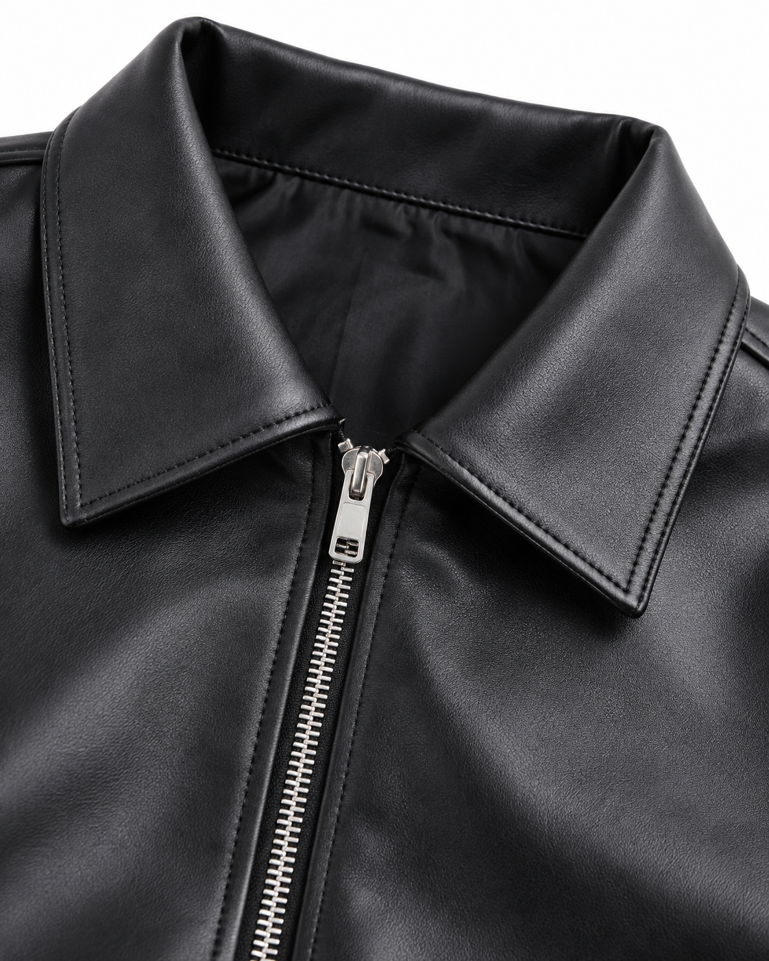 Black leather jacket detail with pointed collar and metal zipper with pull tab.