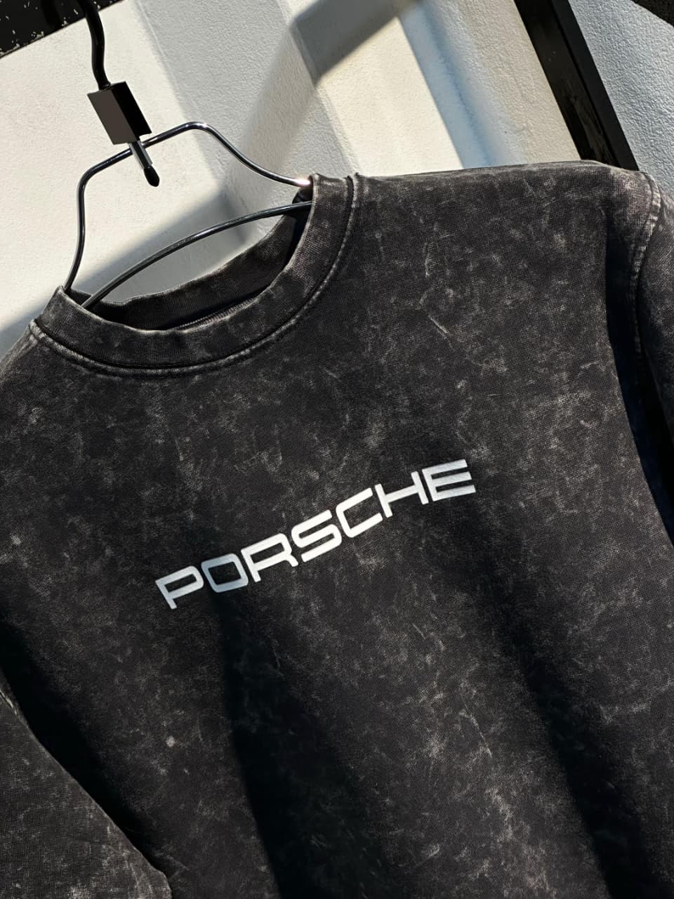 Dark acid-wash T-shirt close-up with large PORSCHE logo across the chest
