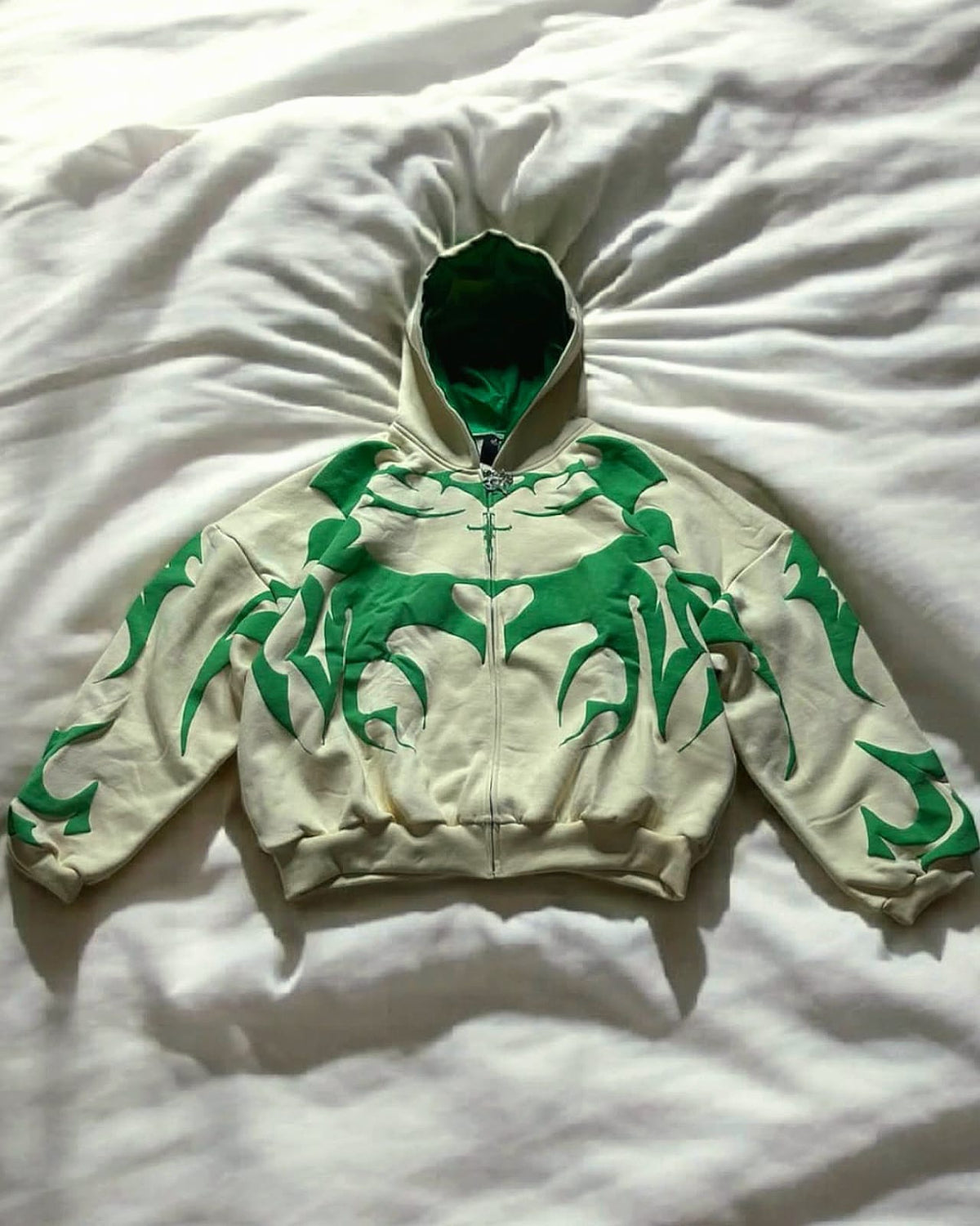 Cream hoodie with green tribal graphic, full-zip front, and hood drawstrings