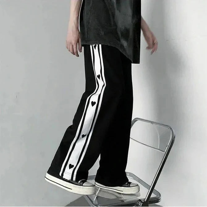 Black baggy track pants with long white stripe and heart print, full-length