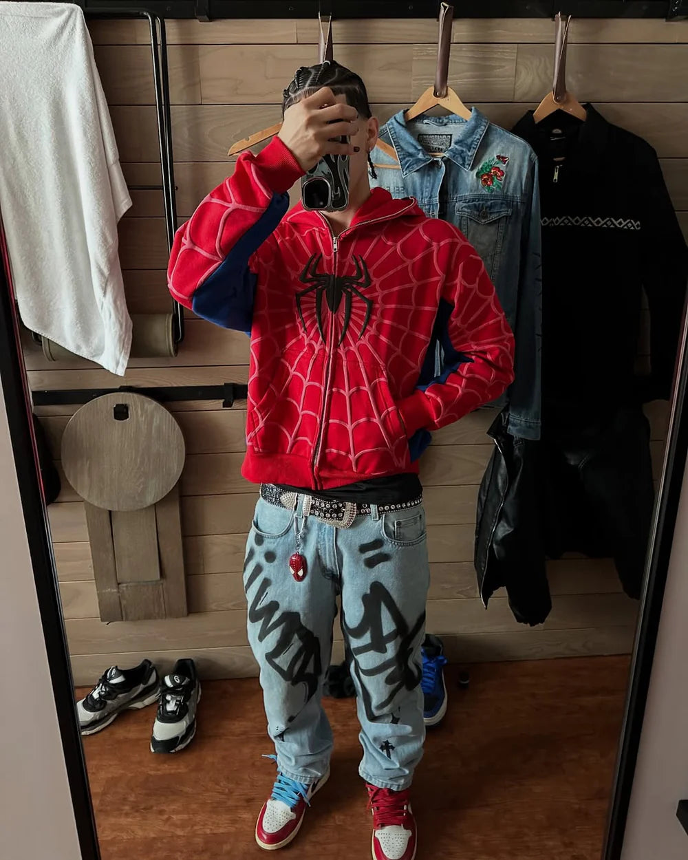 Red zip-up hoodie with spider-web print, blue sleeve panels, and drawstring hood